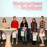 Personen auf der Bühne vor einer Projektionsfläche