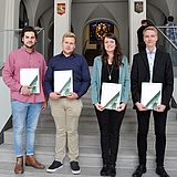 Vier Personen halten Dokumente auf einer Treppe