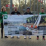 Vier Personen halten ein TU Clausthal-Banner