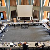 Personen sitzen an einem quadratischen Tisch
