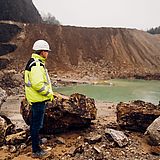 Eine Person steht in einer Ausgrabungsstätte vor einem kleinen See