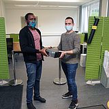 Eine Person gibt einer anderen einen Computer