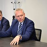 Eine Person mit den Händen auf dem Tisch spricht während einer Besprechung mit anderen