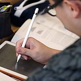 Eine Person schreibt mit einem Stift auf ihr iPad